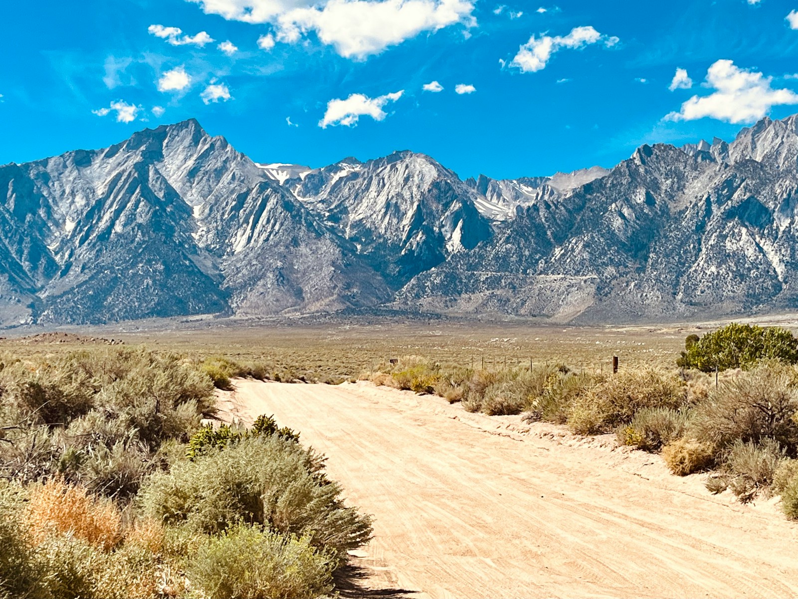 a dirt road in front of a mountain range